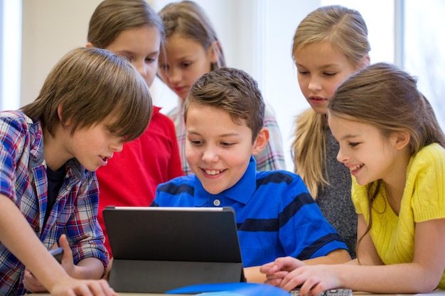 education, elementary school, learning, technology and people concept - group of school kids with tablet pc computer having fun on break in classroom