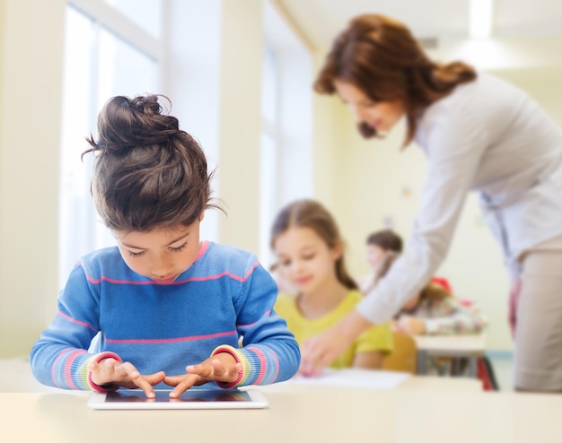 사진 교육, 초등학교, 기술 및 어린이 개념 - 교실 및 교사 배경 위에 태블릿 pc가 있는 어린 학생 소녀