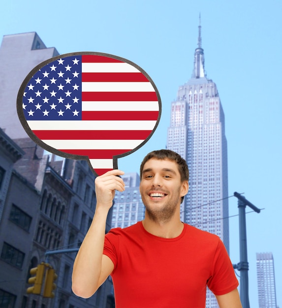 education, foreign language, english, people and communication concept - smiling young man holding text bubble of american flag