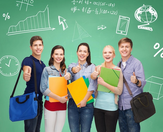 education, friendship and people concept - group of smiling students with folders and bags showing thumbs up over green board