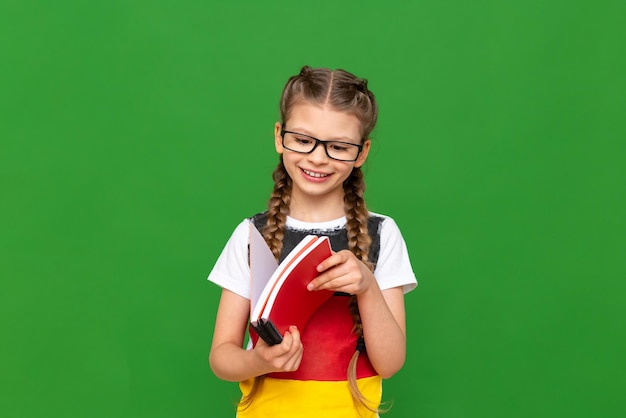 Education in Germany for children A little girl with a German flag and notebooks on a green isolated background Learning foreign languages