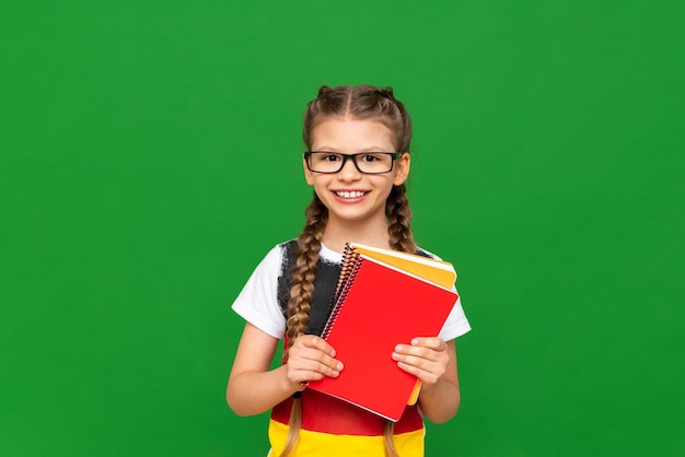 Education in Germany for children A little girl with a German flag and notebooks on a green isolated background Learning foreign languages