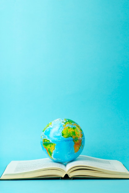 Education and globalism concept. Globe on an open book on a table in a university class on a blue background