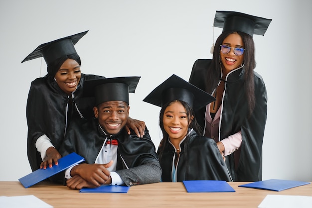 Education, graduation and people concept - group of happy\
international graduate students in mortar boards and bachelor gowns\
with diplomas