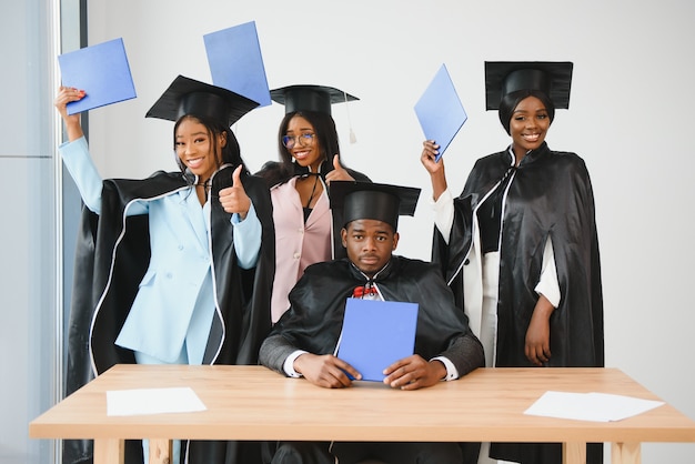 Education, graduation and people concept - group of happy\
international graduate students in mortar boards and bachelor gowns\
with diplomas