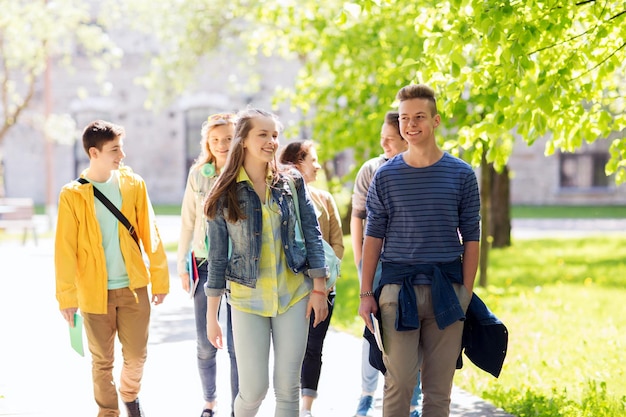 education, high school, communication and people concept - group of happy teenage students walking outdoors