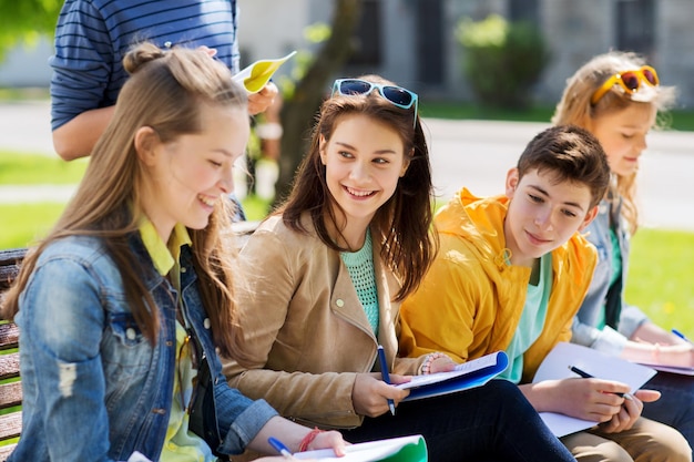 education, high school and people concept - group of happy teenage students with notebooks learning at campus yard