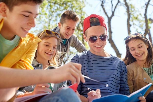 Foto istruzione, scuola superiore e concetto di persone - gruppo di studenti adolescenti felici con quaderni che imparano nel cortile del campus