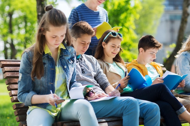 education, high school and people concept - group of happy teenage students with notebooks learning at campus yard