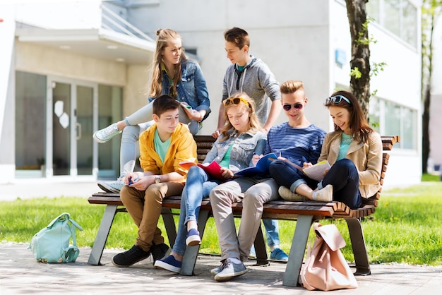 education, high school and people concept - group of happy teenage students with notebooks learning at campus yard