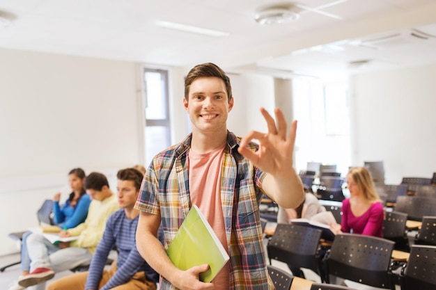 Education, high school, teamwork and people concept - group of
smiling students with notepads showing ok gesture in lecture
hall