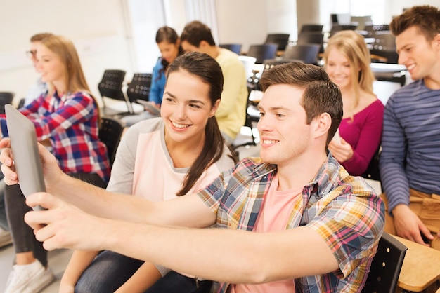 education, high school, teamwork and people concept - group of smiling students with tablet pc computers making photo or video in lecture hall