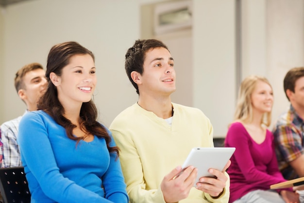 교육, 고등학교, 팀워크 및 사람 개념 - 강의실에 앉아 태블릿 PC 컴퓨터와 함께 웃는 학생들의 그룹