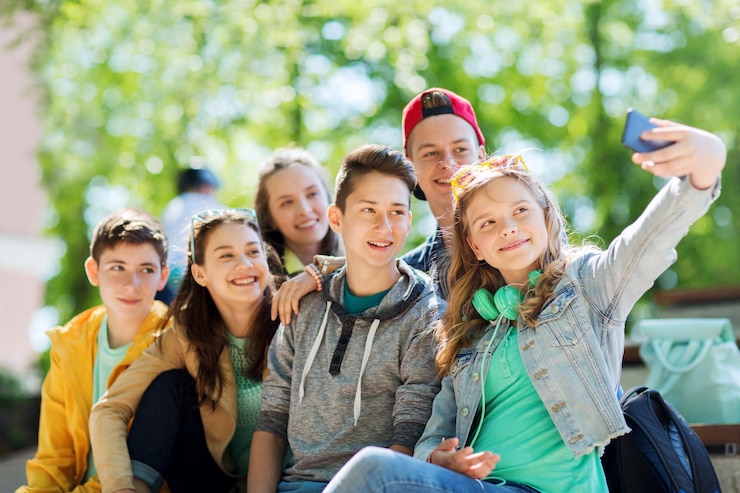Photo education, high school, technology and people concept - group of happy teenage students or friends taking selfie by smartphone