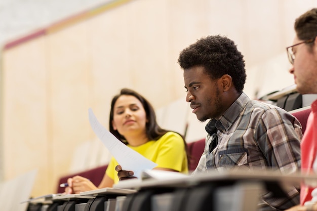 education, high school, university, learning and people concept - group of international students with test in lecture hall