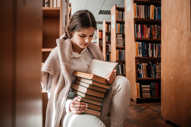 Photo education, high school, university, learning and people concept - smiling student girl reading book at library