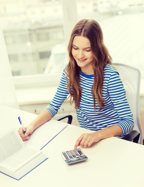 Foto concetto di educazione e casa - ragazza studentessa sorridente felice con taccuino, calcolatrice e libro