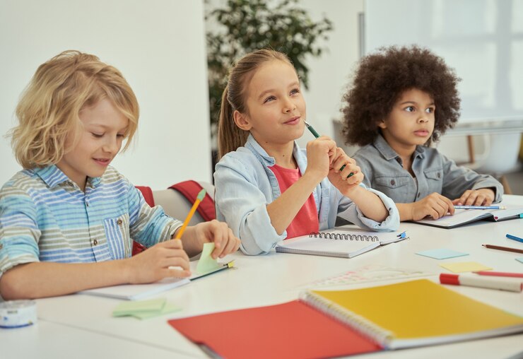 Photo education is key lovely diverse kids studying and making notes while sitting together at the table