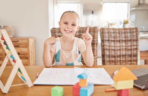 Education learning and child development with girl drawing and doing homework at a kitchen table at home Portrait of a happy student smile enjoying distance learning and educational art project