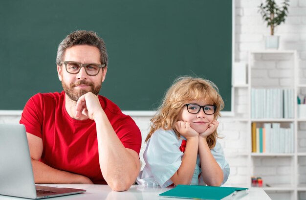 教育と学習の概念 小学校の生徒がレッスンを受けています 先生と一緒に英語や数学を学ぶ少年 父と息子が学校で宿題をしています