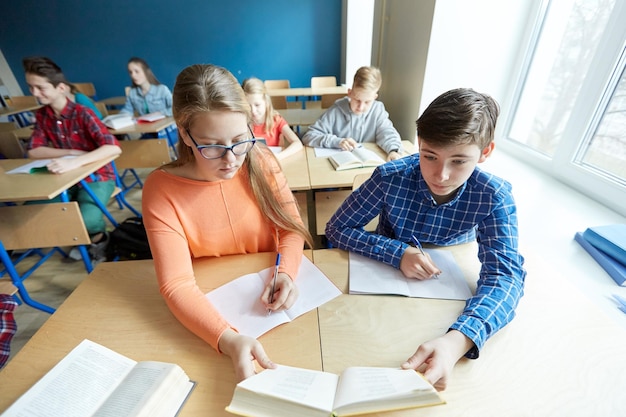 education, learning and people concept - group of students with book reading at school lesson