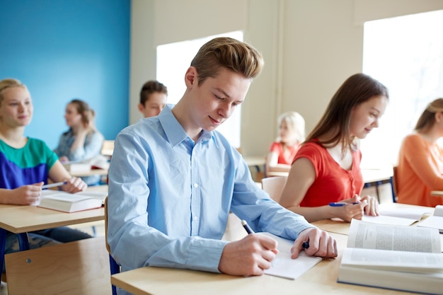 教育学習と人々のコンセプト - 書籍を持った学生のグループが学校のテストを書く