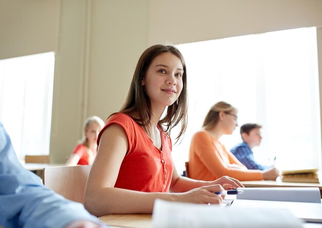 Photo education, learning and people concept - happy student girl with book writing school test