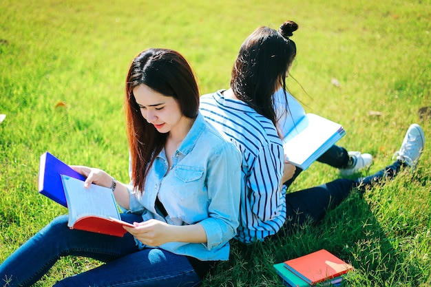 屋外教育 - 緑の草の本を読むアジアの女性大学