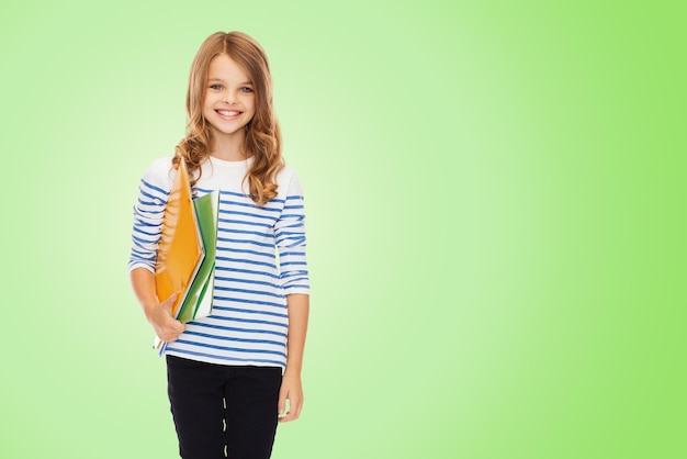 교육, 사람, 어린이, 학교 개념 - 녹색 배경 위에 다채로운 폴더를 들고 있는 행복한 소녀