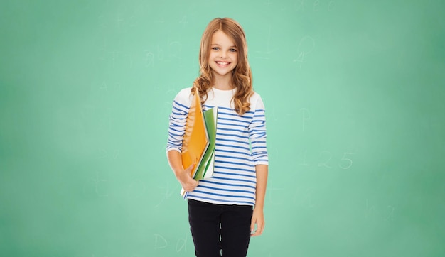 교육, 사람, 어린이 및 학교 개념 - 녹색 보드 배경 위에 다채로운 폴더를 들고 있는 행복한 소녀