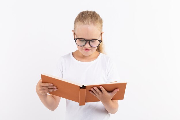 Концепция образования, людей, детей и школы - школьник в очках, держа книгу в руках на белом фоне