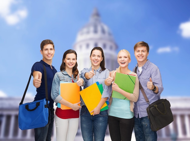 education and people concept - group of smiling students standing and showing thumbs up