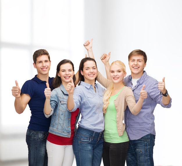 Concetto di educazione e persone - gruppo di studenti sorridenti in piedi e che mostrano i pollici in su