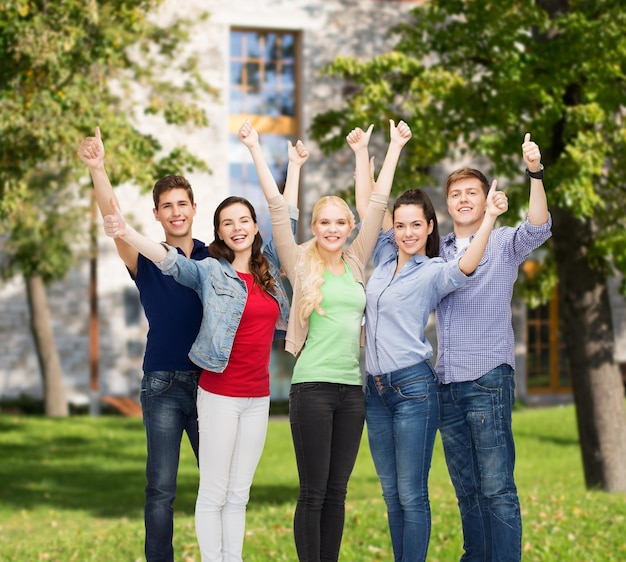 education and people concept - group of smiling students standing and showing thumbs up