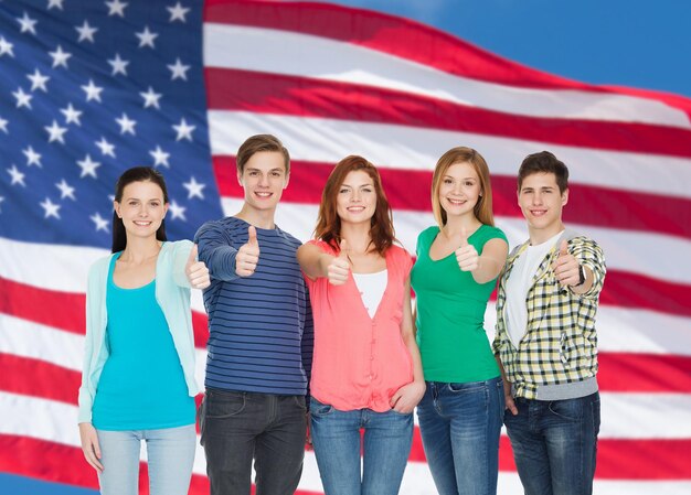 Photo education and people concept - group of smiling students standing and showing thumbs up