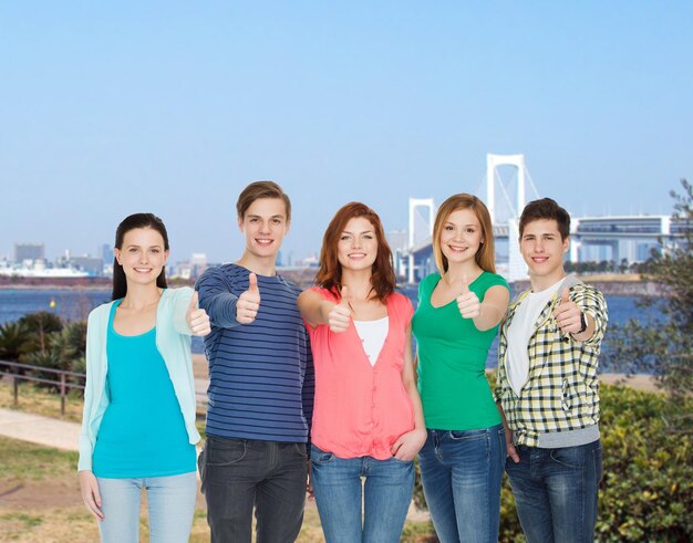 education and people concept - group of smiling students standing and showing thumbs up