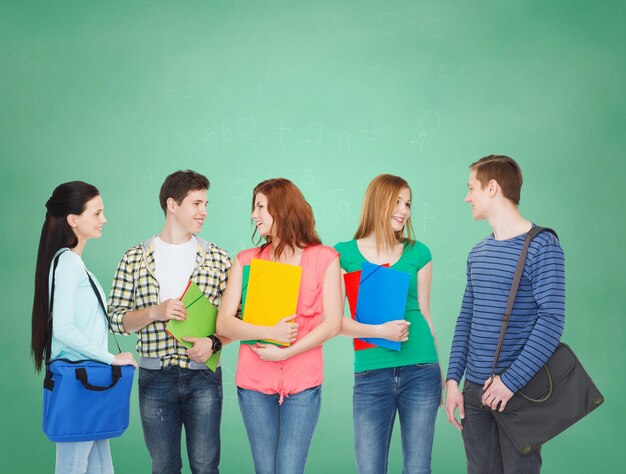 Photo education and people concept - group of smiling students with bags and folders having discussion