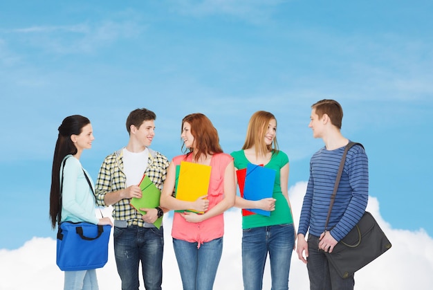 education and people concept - group of smiling students with bags and folders having discussion