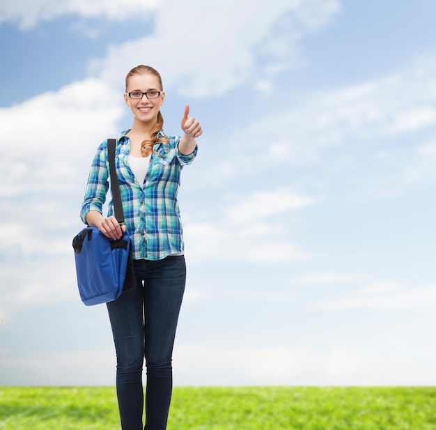 education and people concept - smiling female student in eyeglasses with laptop bag showing thumbs up