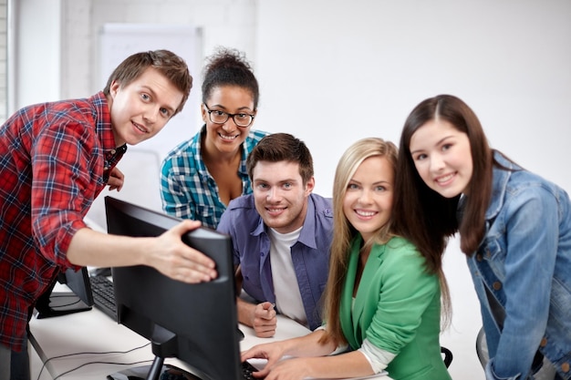 education, people, friendship, technology and learning concept - group of happy international high school students or classmates in computer class