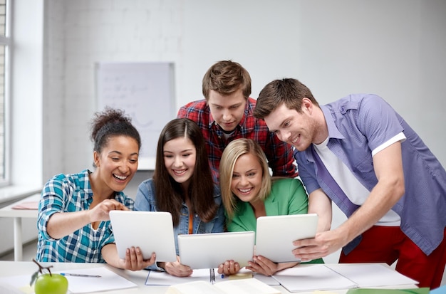 education, people, friendship, technology and learning concept - group of happy international high school students or classmates with tablet pc computer in classroom