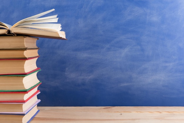 Education and reading concept group of books on the wooden table blue blackboard background Teachers desk