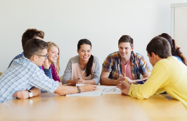 education, school, architecture and people concept - group of smiling students with blueprint meeting indoors