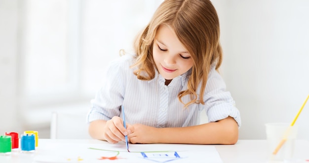 教育、学校、芸術、痛みを伴う概念-学校で絵を描く小さな学生の女の子