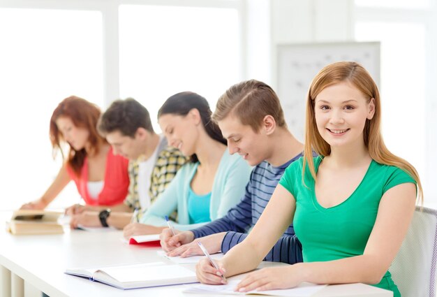 education and school concept - five smiling students with textbooks and books at school