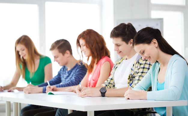 education and school concept - five smiling students with textbooks at school