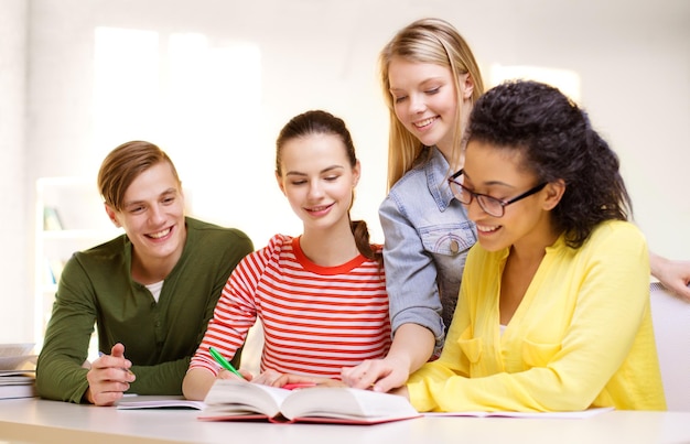 Foto concetto di istruzione e scuola - quattro studenti sorridenti con libri di testo e libri a scuola