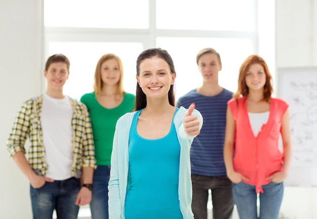 education and school concept - group of smiling students with teenage girl in front showing thumbs up