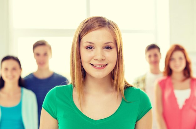 education and school concept - group of smiling students with teenage girl in front