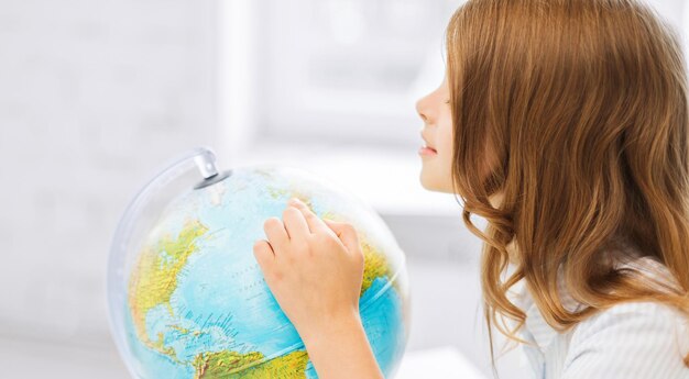 education and school concept - little curious student girl with globe at school